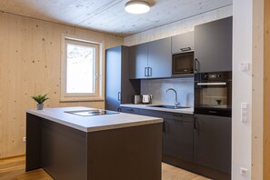 Eine moderne Küche mit Kochinsel, eingebauten Geräten und einem Fenster, das für natürliches Licht sorgt.