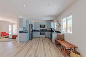 A modern kitchen with light blue cabinets, stainless steel appliances, and a wooden floor. - Juniper & Sage Retreat - 3 bed, Pool, Spa & Stargazing Near Joshua Tree (Joshua Tree)