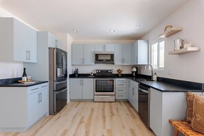 Une cuisine moderne avec des meubles de couleur bleu clair, des appareils en acier inoxydable et un plancher en bois.