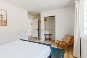 A bedroom with a bed, a chair, a wardrobe, and a door leading to another room. - Juniper & Sage Retreat - 3 bed, Pool, Spa & Stargazing Near Joshua Tree (Joshua Tree)