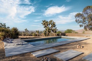 A swimming pool with lounge chairs and a view of mountains. - Juniper & Sage Retreat - 3 bed, Pool, Spa & Stargazing Near Joshua Tree (Joshua Tree)