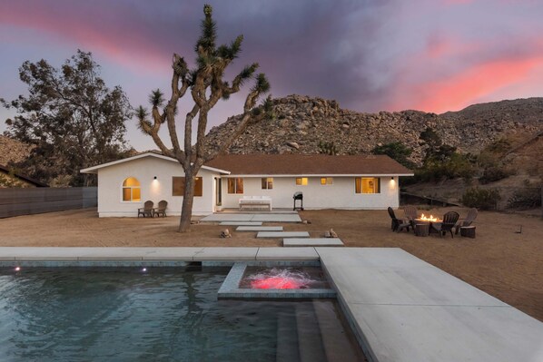 Une maison avec une piscine, un espace extérieur aménagé et un paysage désertique.