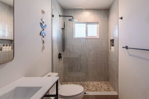 Une salle de bain moderne équipée d’une douche, de toilettes et d’un lavabo.