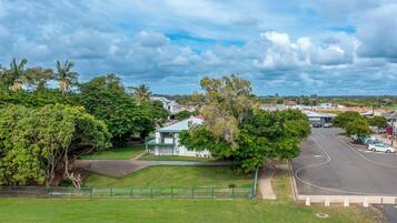 A residential area with a white house, green fence, and a road.