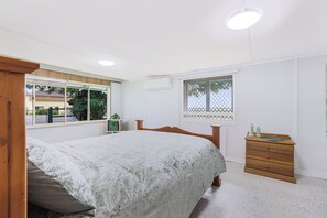 A bedroom with a bed, a dresser, a window, and a ceiling light. - Ocean Soul Unit 2 (Burnett Heads)