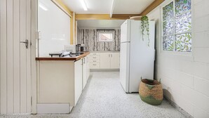 A narrow kitchen with white cabinets, a microwave, and a refrigerator. - Ocean Soul Unit 2 (Burnett Heads)