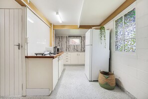 A narrow kitchen with white cabinets, a microwave, and a refrigerator. - Ocean Soul Unit 2 (Burnett Heads)