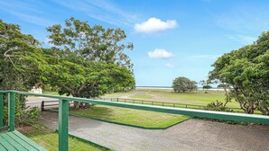 A view from a balcony with a gravel path, green railing, and trees. - Ocean Soul Unit 2 (Burnett Heads)