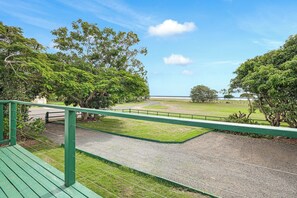 A view from a balcony with a gravel path, green railing, and trees. - Ocean Soul Unit 2 (Burnett Heads)