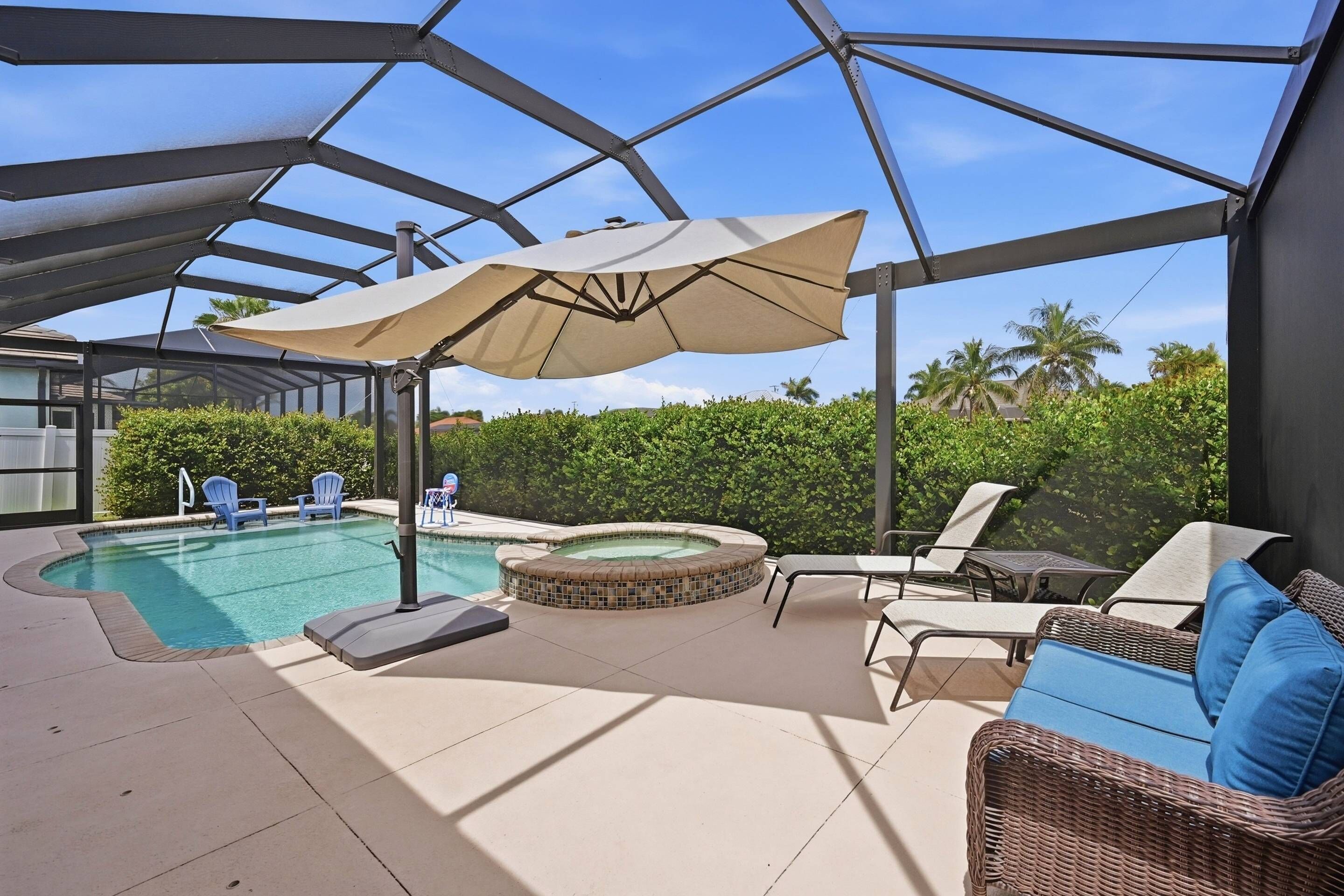 A covered outdoor area with a pool, lounge chairs, and a hot tub.