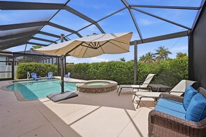 Ein überdachter Außenbereich mit Pool, Liegestühlen und Whirlpool.