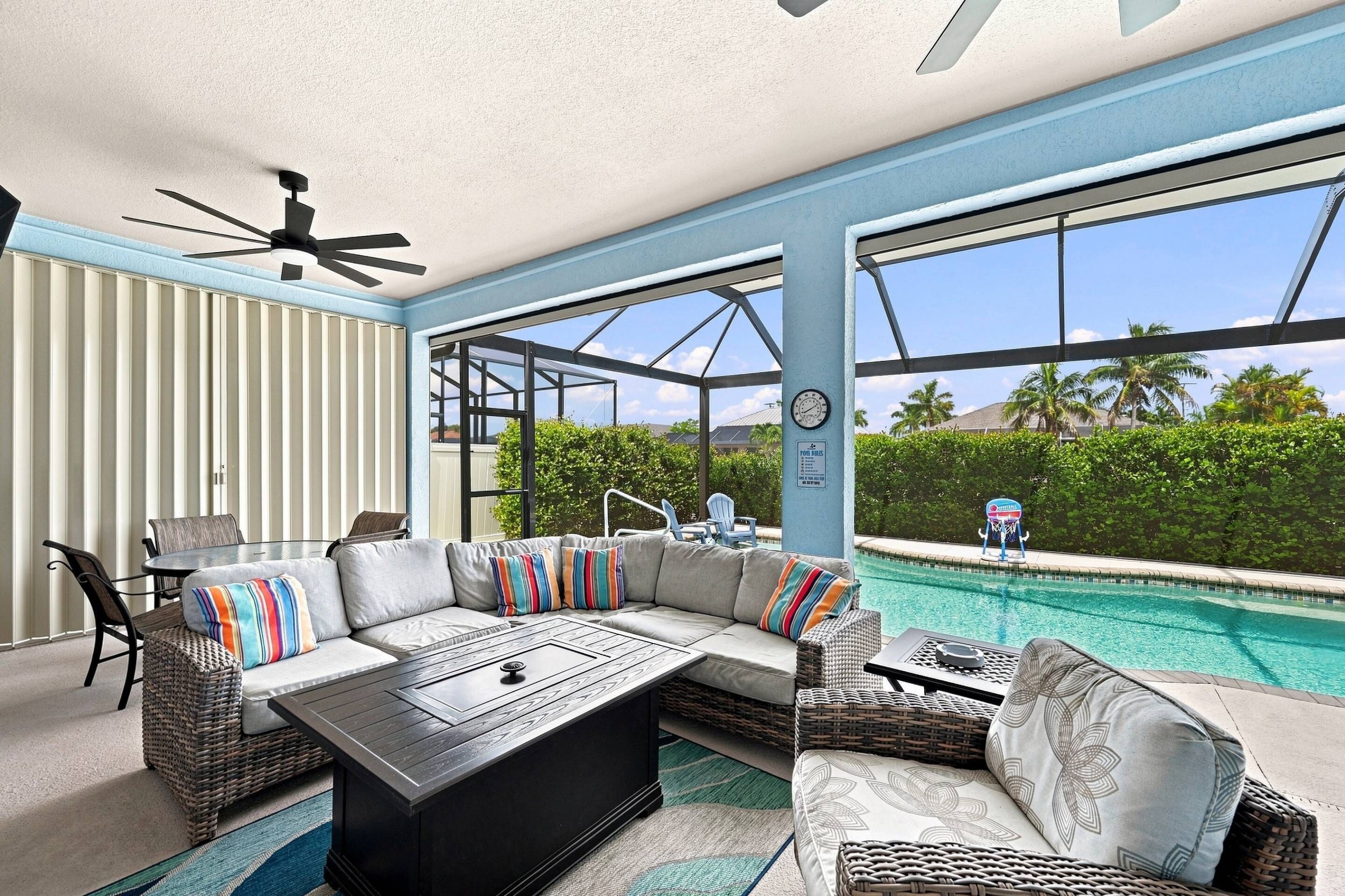 Un espace aménag é au bord de la piscine, comprenant un canapé d’angle, une table à manger et un ventilateur de plafond.