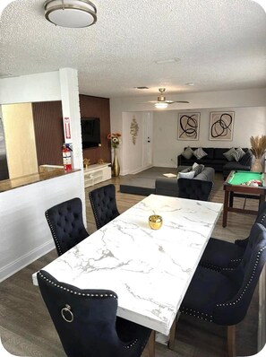 A modern dining area with a marble table and upholstered chairs, a living room with a sofa and abstract art, and a kitchen with wooden accents and a fire extinguisher. - Bright Oasis, 🏝️Private 4BR Pool&Jacuzzi 🛟 Sleeps 14 🛌 . Hollywood  (Hollywood)