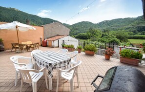 An outdoor patio with a table and chairs, surrounded by potted plants and a view of a hilly landscape. - 3 bedroom nice apartment in Conca Casale (Conca Casale)