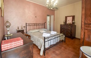 Ein Schlafzimmer mit Bett, Nachttischen, einem Schminktisch und einem Kronleuchter.
