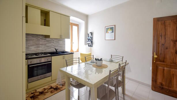 A compact kitchen with a dining area, featuring a stove, oven, and a table set for four. - 3 bedroom nice apartment in Conca Casale (Conca Casale)