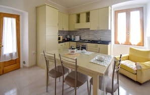 A compact kitchen with a dining table, chairs, and a sofa. - 3 bedroom nice apartment in Conca Casale (Conca Casale)