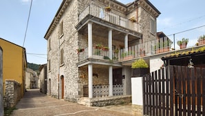 A stone building with a balcony, a wooden gate, and a narrow street. - 3 bedroom nice apartment in Conca Casale (Conca Casale)