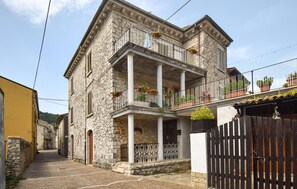 Ein Steinhaus mit Balkon, einem Holztor und einer schmalen Straße.