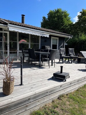 Ett takförsett utomhusområde med bord och stolar, en skorsten och ett trädäck.