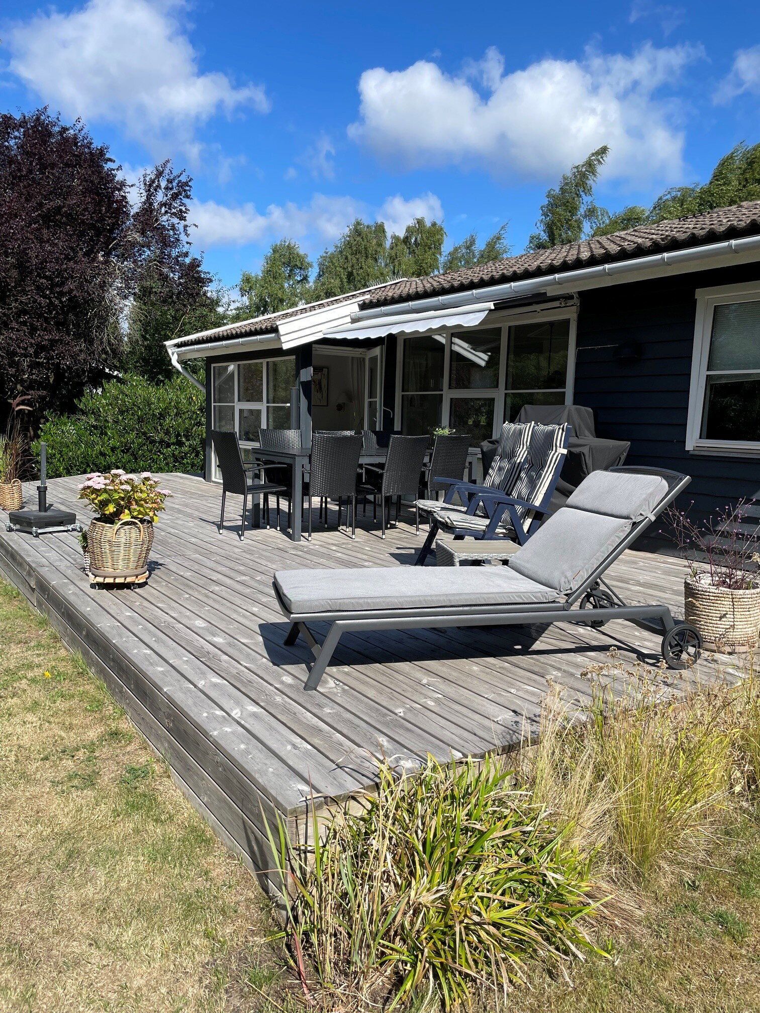 A deck with outdoor furniture, including lounge chairs and a table, overlooking a backyard.