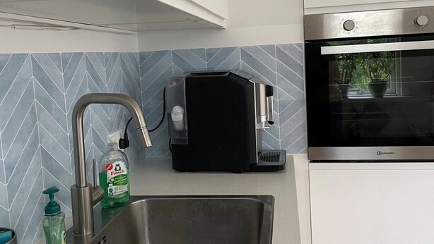 Eine Küche mit einer Edelstahlspüle, einer Bosch-Kaffeemaschine und einem Einbauofen.