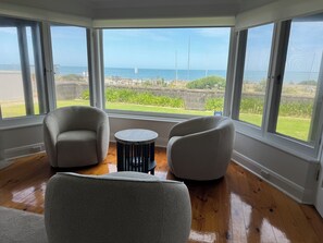 A room with two armchairs, a small round table, and large windows offering a view of the sea and greenery. - Best location with sea views. Enjoy the simple beach life with close amenities. (Victor Harbor)