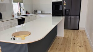 Eine moderne Küche mit weißen Schränken, einem schwarzen Kühlschrank und Holzboden.