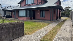 Ein zweistöckiges Haus mit einem großen Fenster, einer überdachten Veranda und einem gepflegten Rasen.