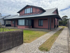 A two-story house with a large window, a covered porch, and a well-maintained lawn. - Best location with sea views. Enjoy the simple beach life with close amenities. (Victor Harbor)