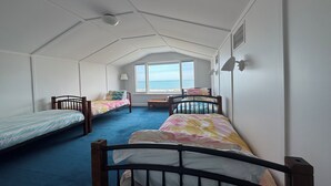 Ein Schlafsaalzimmer mit zwei Betten, einem Fenster und Meerblick.