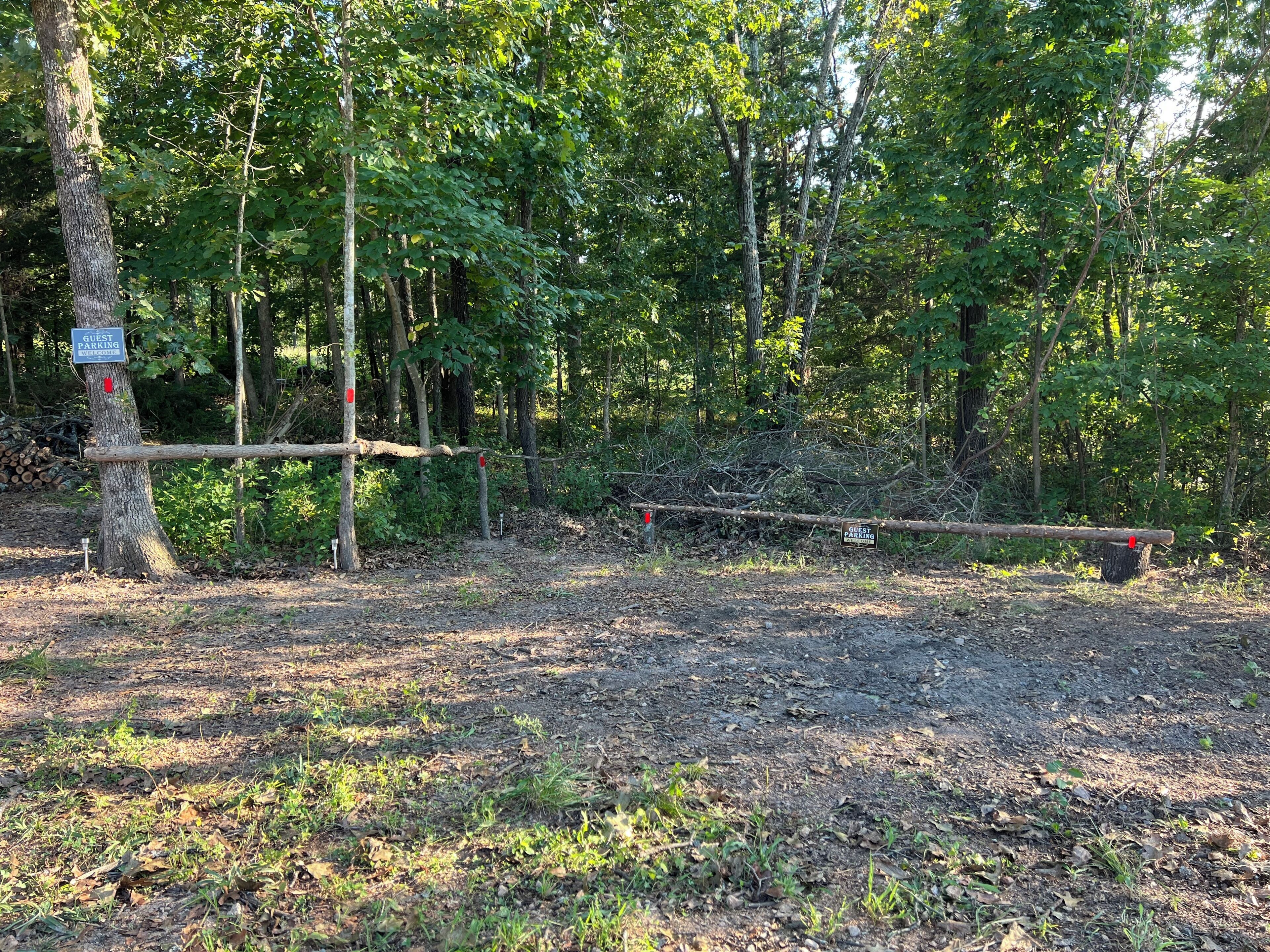 A forested area with a guest parking sign and a wooden barrier.