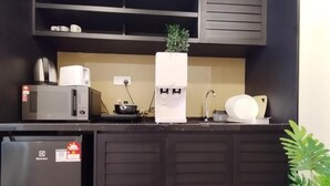 Et kompakt køkken med mikroovn, kaffemaskine og et lille køleskab.