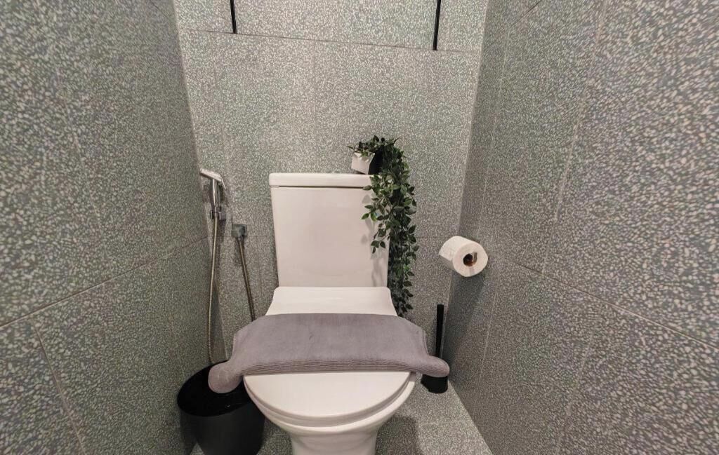 A bathroom with a toilet, a shower, and a towel rack.