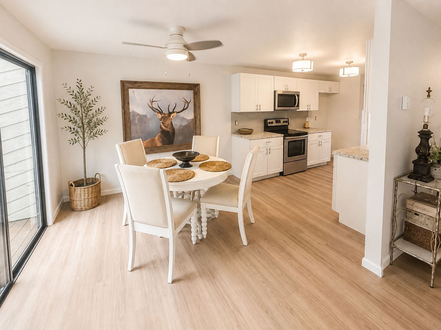 A modern kitchen with white cabinets, a microwave, an oven, and a dining area with a table and chairs.