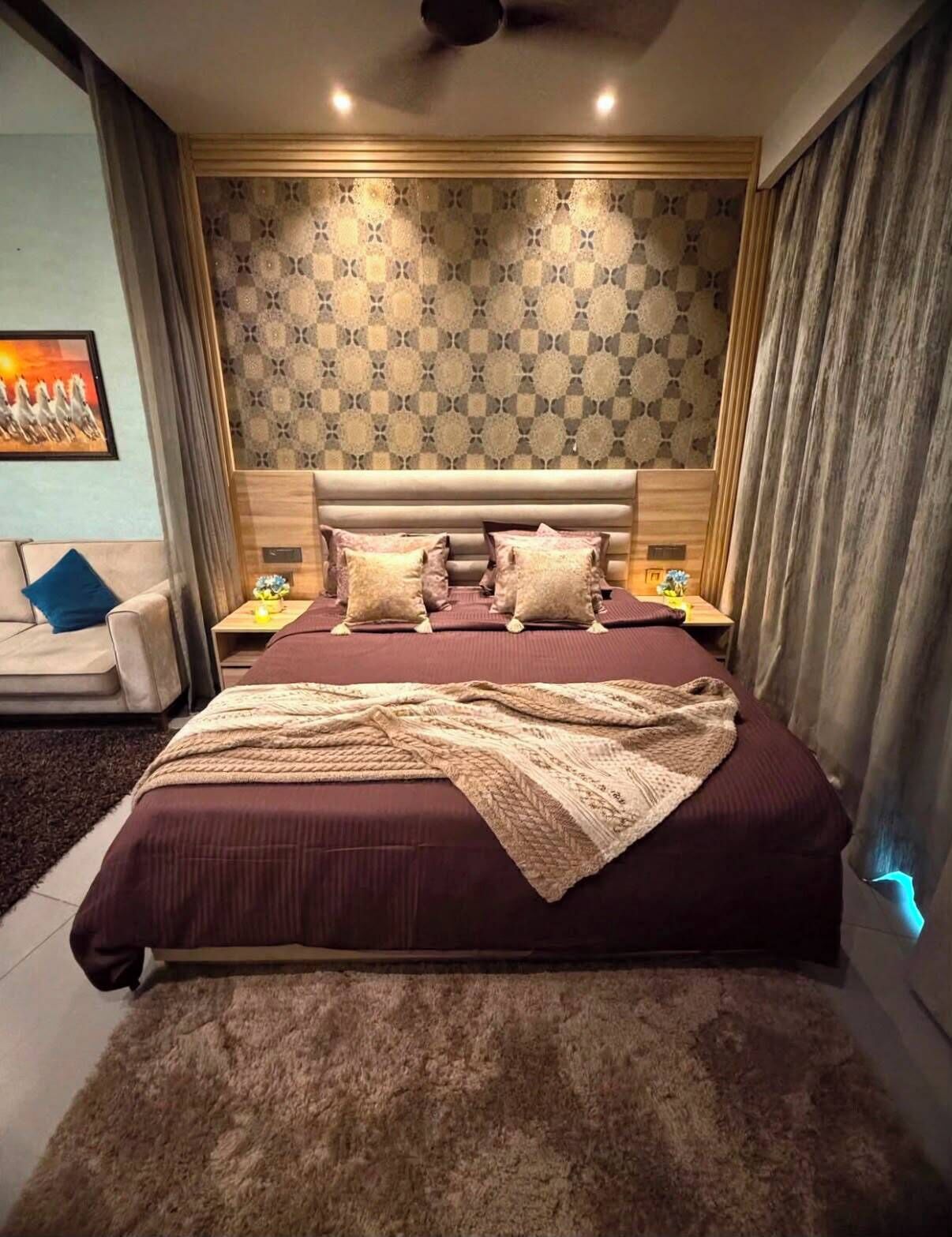 Une chambre à coucher avec un grand lit, une tête de lit, des tables de chevet et un mur décoré d’un motif.