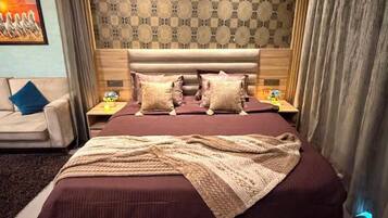 Une chambre à coucher avec un grand lit, une tête de lit, des tables de chevet et un mur décoré d’un motif.