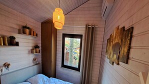 A bedroom with a bed, a hanging light fixture, a window, and wall-mounted decor. - Beautiful Bungalow in Nature (Getelo)