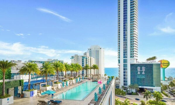 Un hotel con piscina sul tetto, palme e vista sull'oceano.