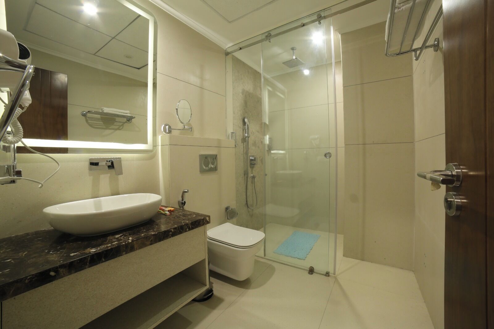 Et moderne badeværelse med en glasafskærmet brusekabine, en hvid vask og et toilet.