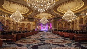A grand hall with ornate chandeliers, a patterned carpet, and rows of seating. - La Flora Resort (Meerut)