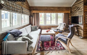Ein gemütliches Wohnzimmer mit einer Couch, Sesseln, einem Couchtisch und einem Fernseher.