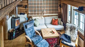 A cozy cabin interior with a sofa, two chairs, a table, a fireplace, and a window. - 3 bedroom cozy apartment in Ustaoset (Ustaoset)
