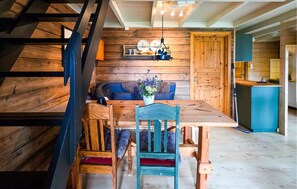 A wooden interior with a dining table, chairs, a sofa, and a hanging light fixture. - 3 bedroom cozy apartment in Ustaoset (Ustaoset)