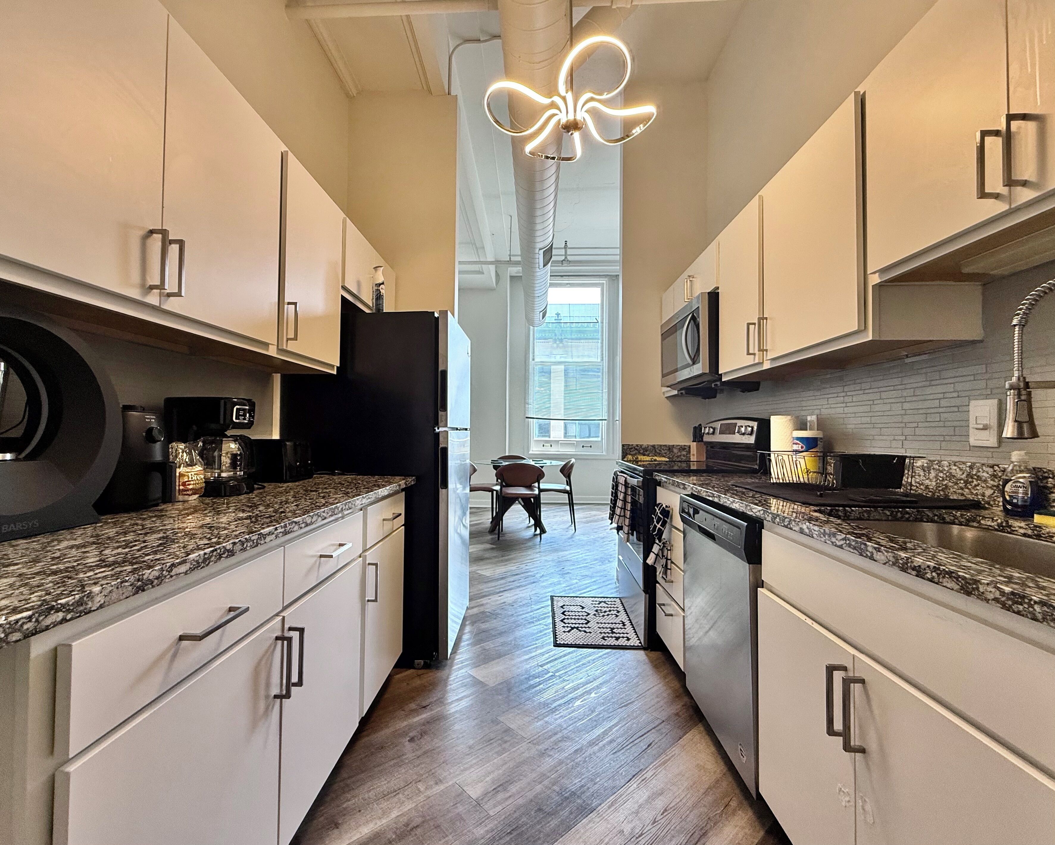 A modern kitchen with white cabinets, granite countertops, a built-in oven, and a central island with seating.