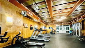 Un gimnasio con cintas de correr, bicicletas estáticas y máquinas de pesas.