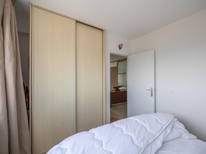 Een slaapkamer met een bed, een garderobe en een deur naar een andere kamer.
