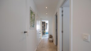 A hallway with white walls, a wooden floor, and a bookshelf in the background. - Three-bedroom apartment with sea view (Middelkerke)