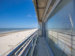 Ein Balkon mit Blick auf einen Strand und einen Parkplatz.