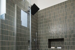 Ein modernes Badezimmer mit Duschbereich, geflieste Wände und einer integrierten Ablage für Toilettenartikel.